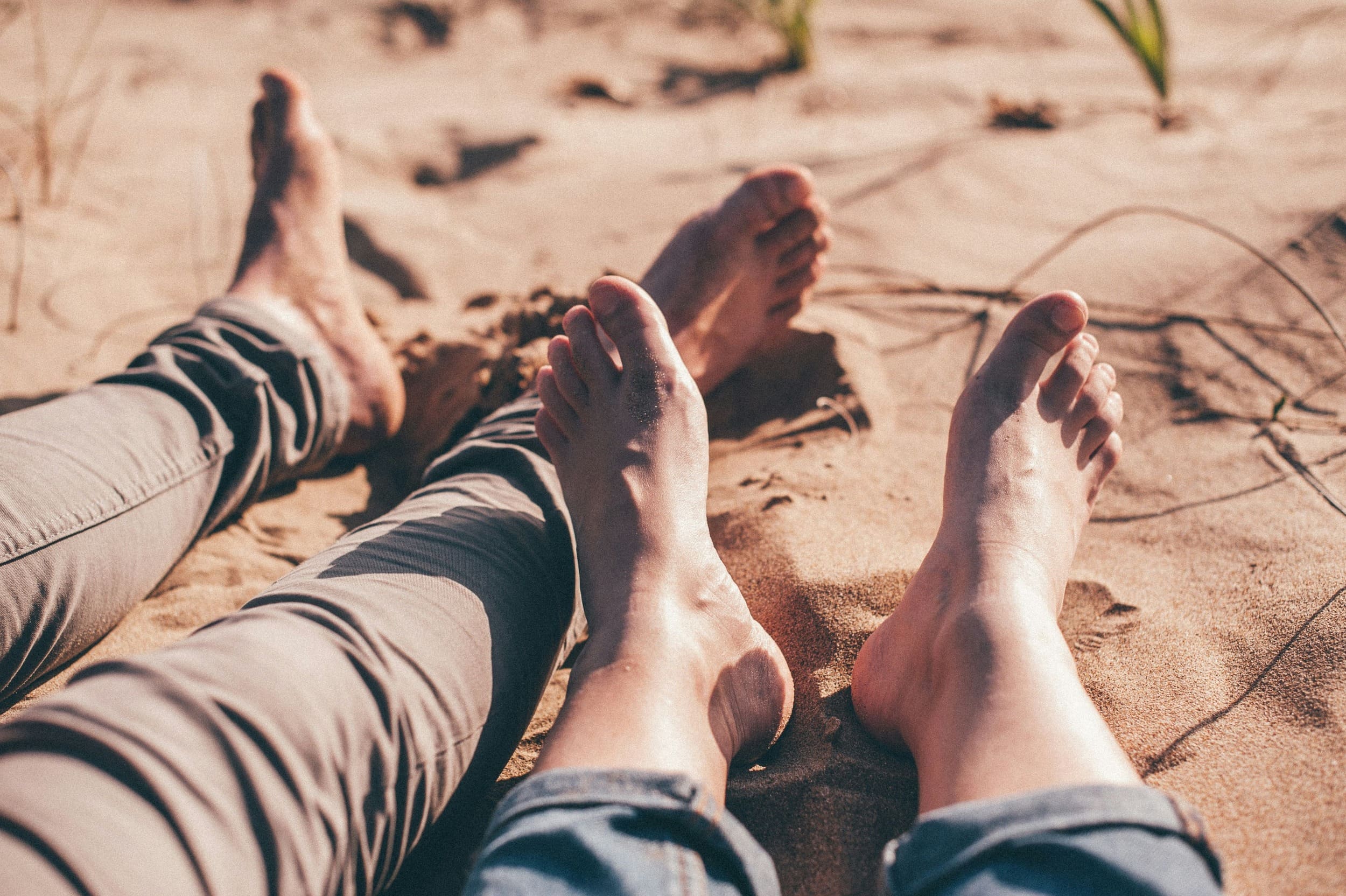 Cabecdera con Pies Pies descalzos de dos personas bonitos en sobre la arena de una playa